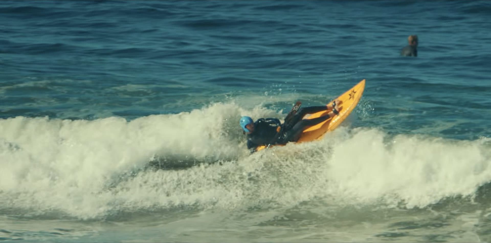 Davy driving off the bottom on the orange waveski as the wave folds over
